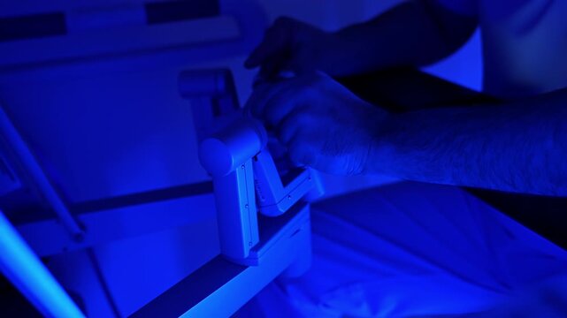 Hairy male hands hold tight the manipulators of modern surgical equipment. Medic performing surgery with the help of robotic system.