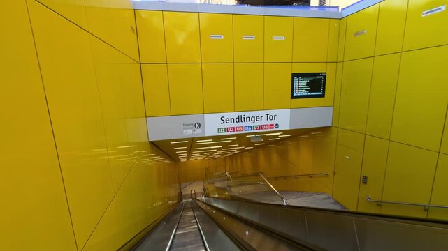 Sendlinger Tor metro entrance in Munich features bright yellow walls, clear U Bahn line signs and descending escalator, capturing modern design and busy urban transit of city transport network