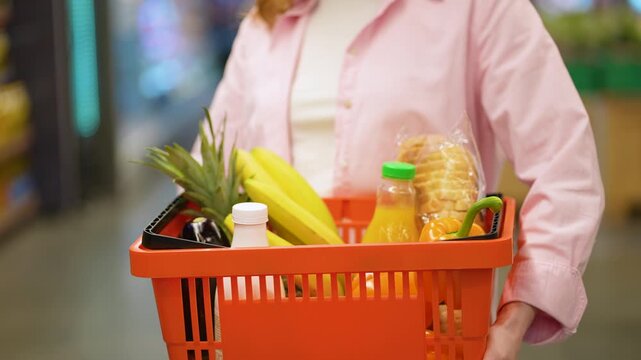 Woman with shopping basket full of groceries in supermarket