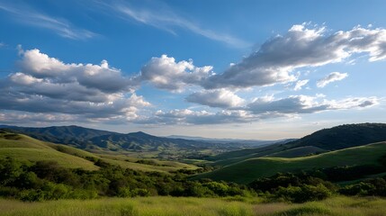 Obraz premium A panoramic view of lush green rolling hills meeting a bright blue sky filled with scattered white clouds