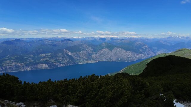 Panoramic time lapse view of Lake Garda from Monte Baldo, featuring shifting clouds, alpine vistas, dramatic shadows, tranquil atmosphere