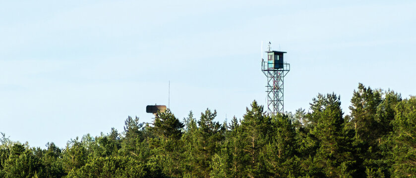 Ultra wide panoramic scene of military observation tower and radar above forest with large sky copy space, surveillance and security concept