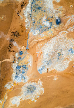 Aerial view of Hverir geothermal area featuring steaming vents, boiling mud pools, and colorful mineral deposits with tourists walking on paths Reykjahlid, THingeyjarsveit, Iceland.