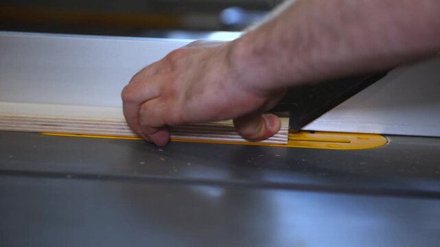 Circular table saw cutting wood in carpenter workshop close up. A running blade on a bench saw sawing trough the wooden log in the middle of a working space, close up footage. A sawing circle that cut