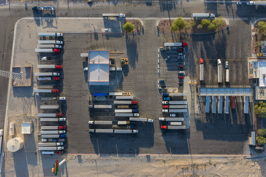 Aerial view of semi-trucks parked in a large logistics lot with asphalt paving and surrounding desert landscape Enterprise, Nevada, United States.