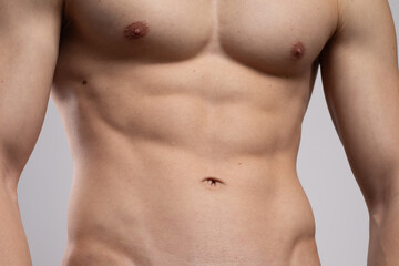 Fototapeta premium A young man with an elastic torso and prominent muscles is dressed in tight jeans after sports. Concept: body parts, men's health. The flexible and agile body of a dancer or athlete