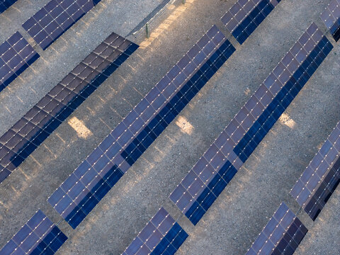 Aerial view of rows of photovoltaic solar panels arranged in a grid on a desert landscape with soft shadows in Enterprise, Nevada, United States.