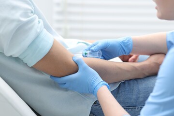 Obraz premium Nurse drawing blood sample of patient's vein with syringe in clinic, closeup