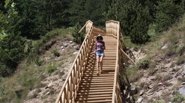 Hike woman is walking down a wooden staircase in a forest hiking trail. The scene is peaceful and serene, with the woman enjoying the natural surroundings