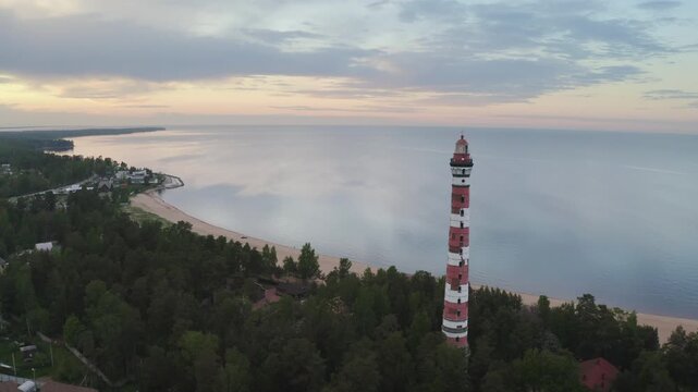 Forward reveal drone footage of Osinovetsky lighthouse and Ladoga lake at sunset. Ladozhskoye Osero village, Leningrad Oblast, Russia.