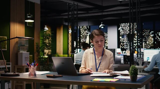 Woman accountant writing down information and working overtime to finish paperwork task before deadline. Bookkeeper working for company and documenting business intel, data insights.