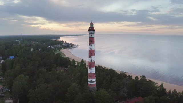 Orbital aerial shot of Osinovetsky lighthouse and Ladoga lake on summer sunset. Ladozhskoye Osero village, Leningrad Oblast, Russia.