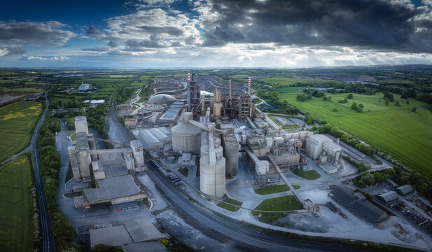 Aerial view of Irish Cement Ltd factory with industrial silos and chimneys under a dramatic cloudy sky in Drogheda, County Louth, Ireland.