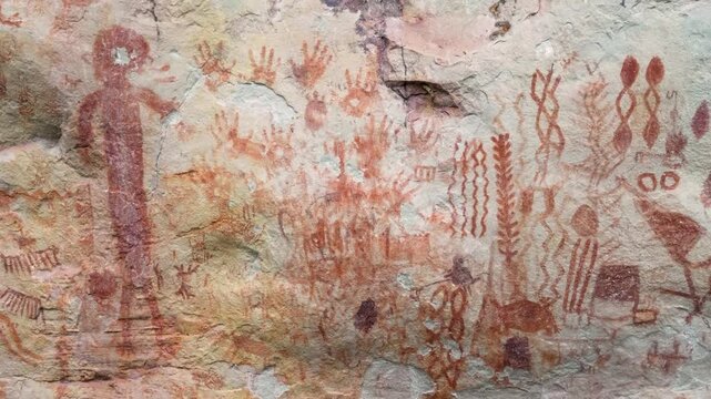 Colorful pictographs of animals and red human figures on a rocky surface with intricate patterns.