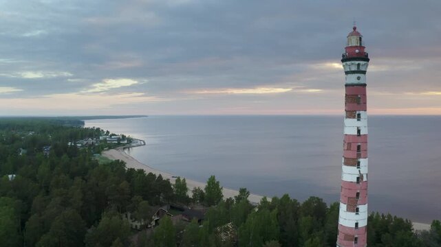 Backward reveal aerial shot of Osinovetsky lighthouse on summer sunrise. Ladozhskoye Osero village, Leningrad Oblast, Russia.