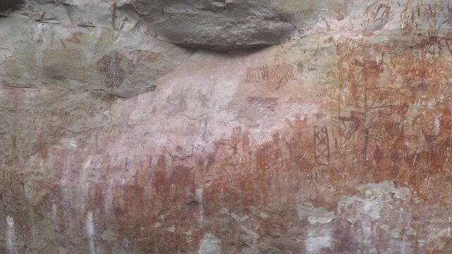 Intricate pictographs on an ancient rock surface showcase vibrant red hues and complex designs.