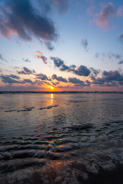 View of the sunset over Strand Wijk aan Zee with sea foam on the sandy beach and dramatic clouds Wijk aan Zee, North Holland, Netherlands.