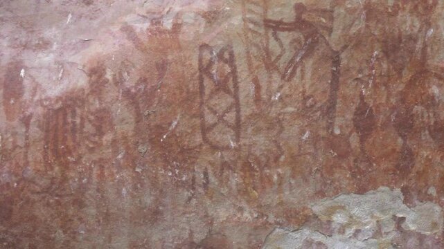 Colorful rock art depicting ancient figures and symbols on a weathered stone surface.