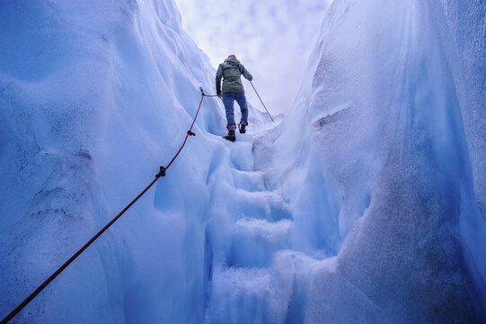Woman walking steps out of a ice cave in Fox Glacier, South Island, New Zealand