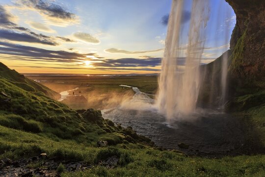 Seljalandsfoss at sunset, next to two people, silhouettes at the photo shoot, Su&eth;urland, Sudurland, near ring road, South Iceland, Iceland