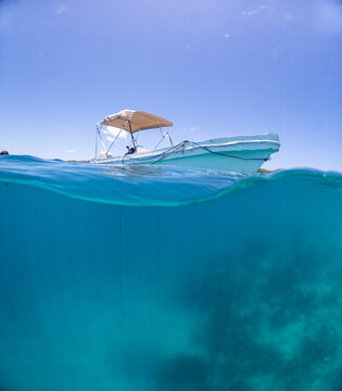 View of a small boat floating on the turquoise Caribbean sea with a clear blue sky in Guanaja, Bay Islands Department, Honduras.