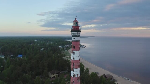 Orbital aerial shot of Osinovetsky lighthouse on summer sunrise. Ladozhskoye Osero village, Leningrad Oblast, Russia.