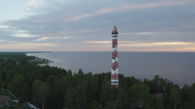 Tilt down aerial shot of Osinovetsky lighthouse and Ladoga lake on summer sunrise. Ladozhskoye Osero village, Leningrad Oblast, Russia.