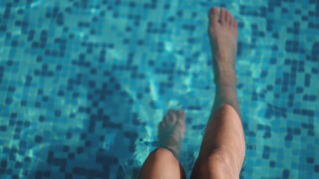 Woman feet are on a pool edge, looking out at the water. Concept of relaxation and leisure, as the person is taking a break from swimming or other activities