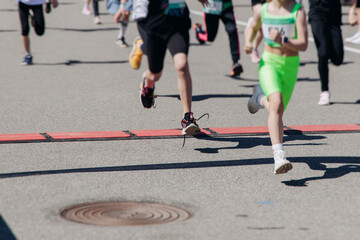 Fototapeta premium Children marathon runners crowd, young teen sportsmen participants start running in the city streets, crowd of kids joggers in motion, kid group athletes outdoor run, family competition in summer day