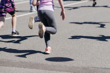 Fototapeta premium Children marathon runners crowd, young teen sportsmen participants start running in the city streets, crowd of kids joggers in motion, kid group athletes outdoor run, family competition in summer day