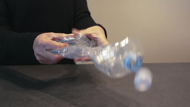 Adult Hands Folding Empty Plastic Water Bottle Recycling Concept