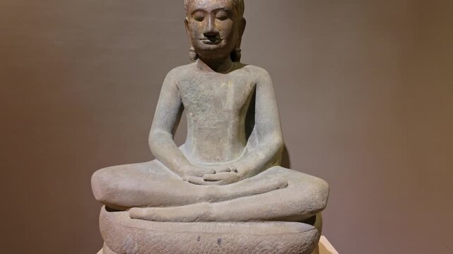 A stone statue of Buddha meditating in a lotus position, seated on a coiled Naga serpent, in the  Angkor National Museum, Siem Reap, Cambodia.