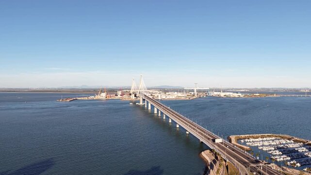 Aerial view of the Constitution of 1812 Bridge in Cadiz, Spain. Cinematic drone shot of the modern landmark cable-stayed bridge over the bay on a sunny day
