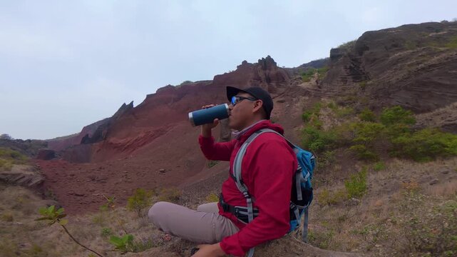 Thirsty hiker drinking water at red earth mines in puebla mexico