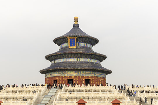 View of the Hall of Prayer for Good Harvests in the Temple of Heaven with tourists walking on white marble terraces under a hazy sky Beijing, Beijing, China.