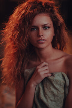 Sensual portrait of a young woman with curly red hair and freckles