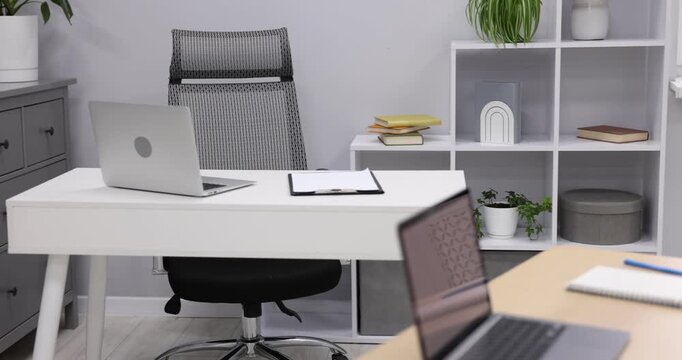 Interior design. Desks with laptops, stationery, other furniture and decor. Camera moving in and left