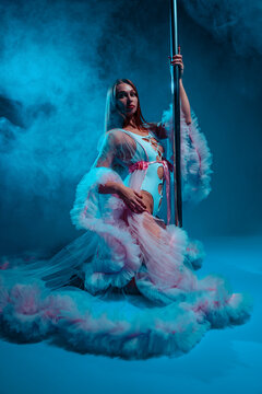 Beautiful pole dancer in a white bodysuit and pink tulle robe