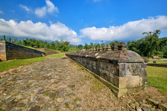 View of the ancient stone walls and cobblestone path at Situs Liyangan archaeological site surrounded by lush greenery and hills in Temanggung, Central Java, Indonesia.