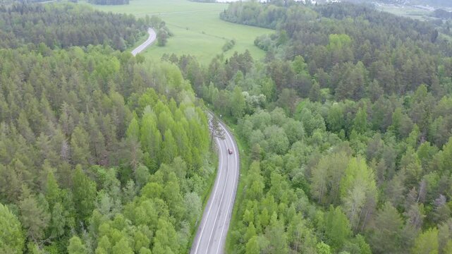 Tracking aerial footage of a car on the Lahdenpohja - Sortavala road on misty summer day. Karelia, Russia.