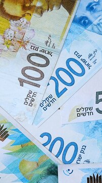 Israeli new shekel money bills in pile on table. Israel ILS currency cash close up
