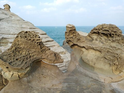 Close up of weathered honeycomb rock formations by the blue sea