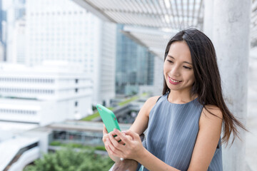 Fototapeta premium Woman using cellphone while standing outdoors in city