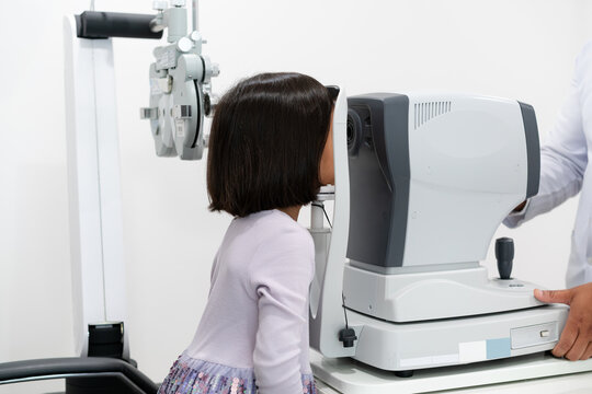 Side view of a young Asian girl placing her chin on an autorefractor machine for an automated vision measurement