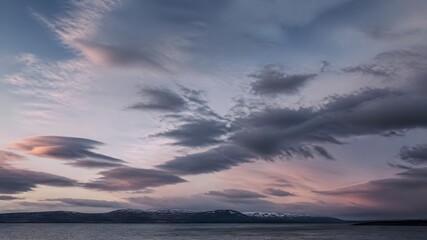 Fototapeta premium Sunburst Breaking Through Dramatic Storm Clouds Over Peaceful Ocean with Pastel Pink Horizon