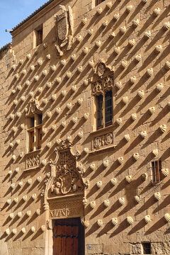 Salamanca, Spain - 01 December 2025: View of the facade of the Casa de las Conchas with its iconic scallop shells, ornate Gothic windows, and stone carvings under bright sunlight.