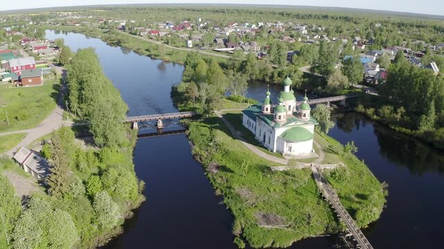 Forward reveal aerial shot of Smolensky cathedral and bridges over Olonka river on sunny summer day. Olonets town, Karelia, Russia.