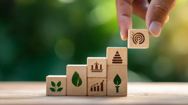 side-view professional photograph of a row of four wooden blocks on a light wood tabletop. A hand is seen fine-tuning the alignment of the last block which illustrates target achievement and 