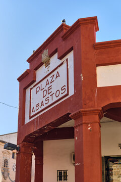 Plasencia, Spain - 03 December 2025: View of the red facade and sign of the Plaza de Abastos market building under a clear blue sky.