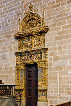 Plasencia, Spain - 03 December 2025: View of the ornate gilded Plateresque doorway of the Catedral Nueva de Plasencia with intricate carvings and religious figures set against a stone wall.